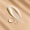 Drops and texture of a facial serum on a beige background